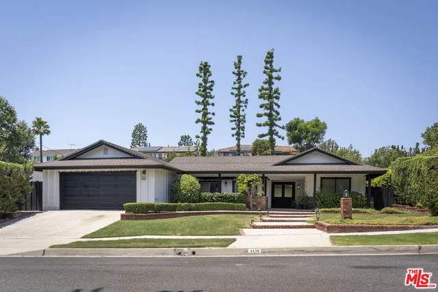 a front view of a house with a garden and plants