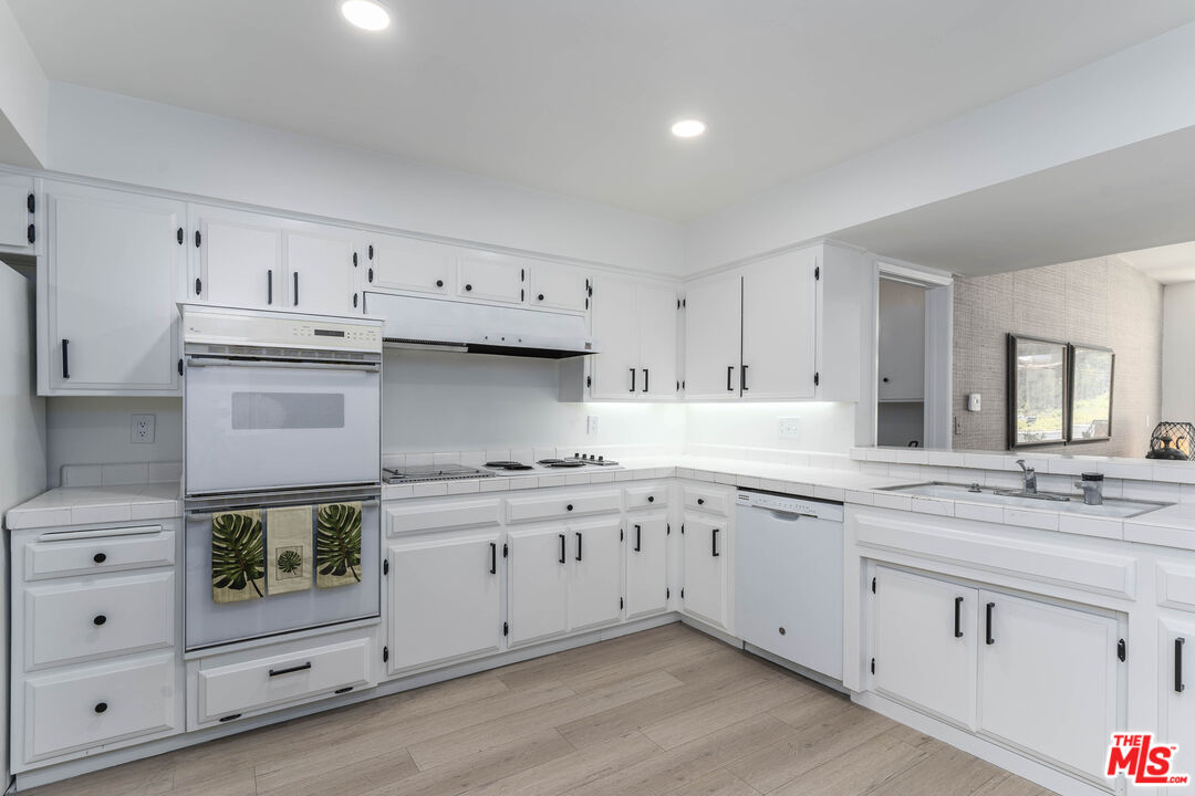 4139 Magna Carta Road Calabasas, CA 91302 - Photo 13 of 33 a kitchen with granite countertop white cabinets and white appliances