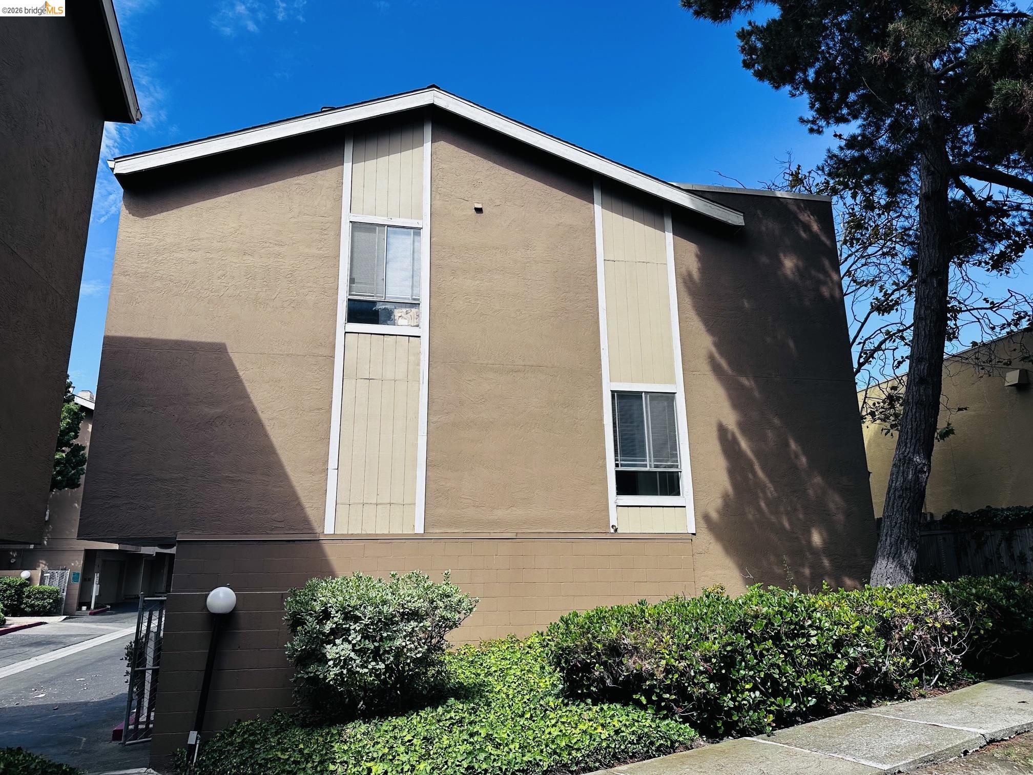 2121 Vale Road, Unit 50 San Pablo, CA 94806 - Photo 3 of 26 Stucco exterior with vertical panel accents, multiple windows, and landscaped shrubbery