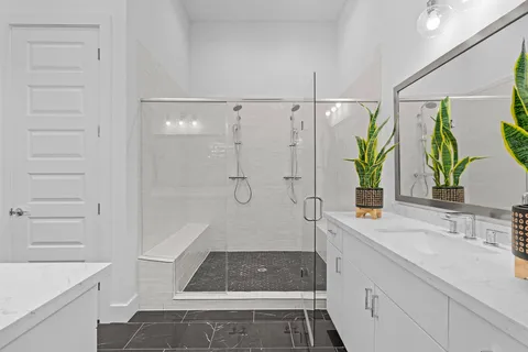 a bathroom with a granite countertop sink a toilet a mirror and shower