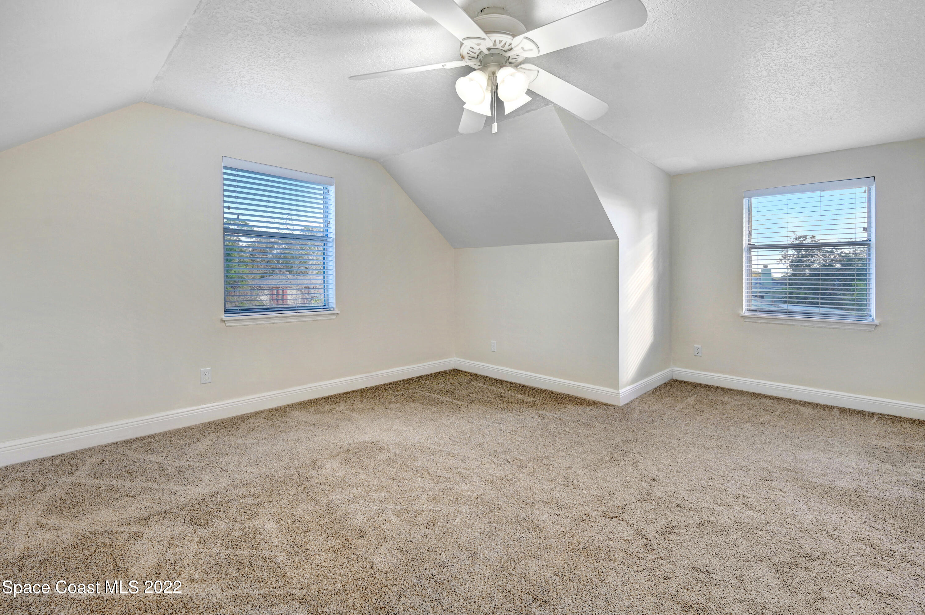 1074 Castile Road Southeast Palm Bay, FL 32909 - Photo 23 of 40 an empty room with a chandelier fan and windows