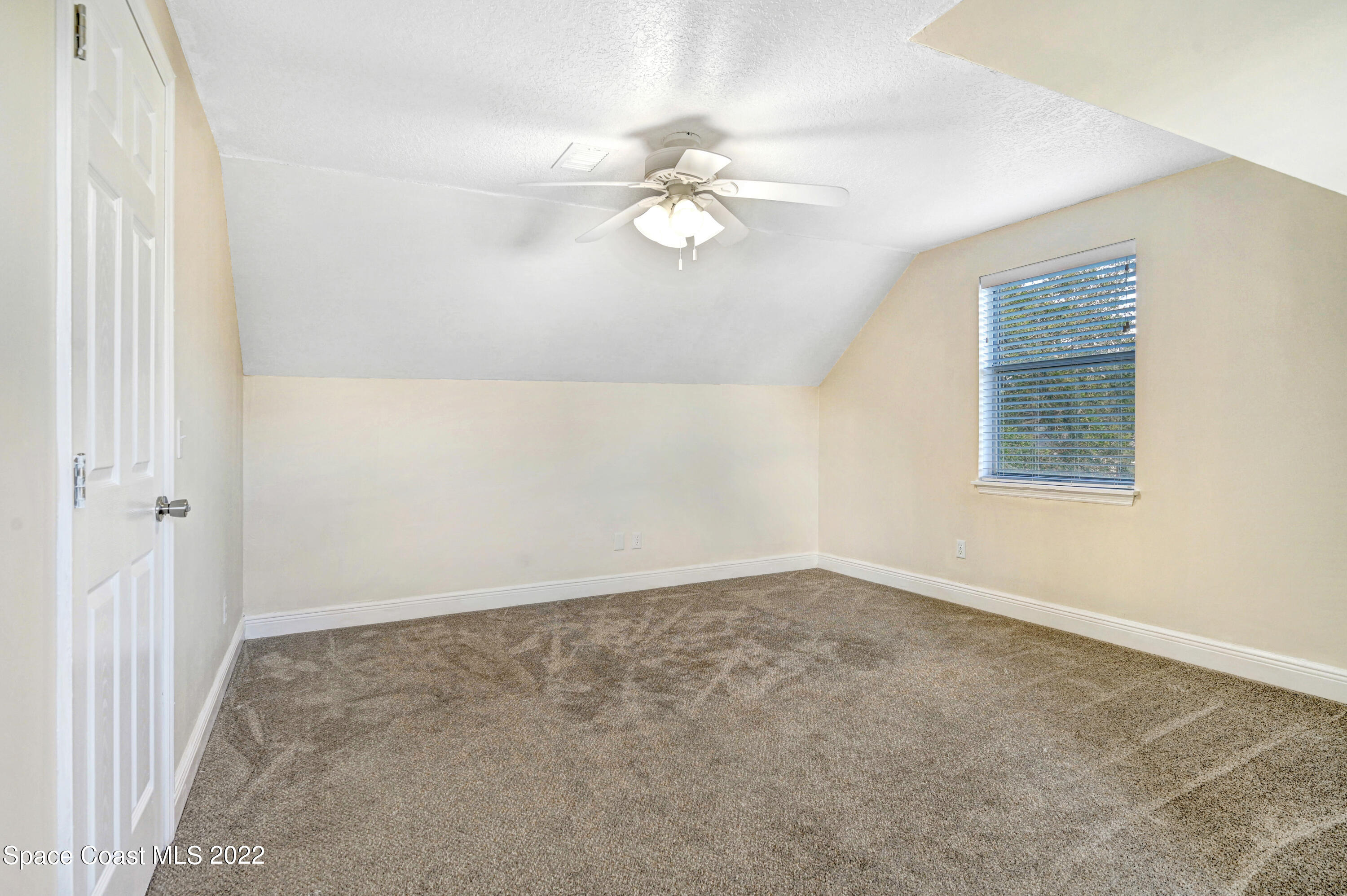 1074 Castile Road Southeast Palm Bay, FL 32909 - Photo 24 of 40 an empty room with a chandelier fan and windows