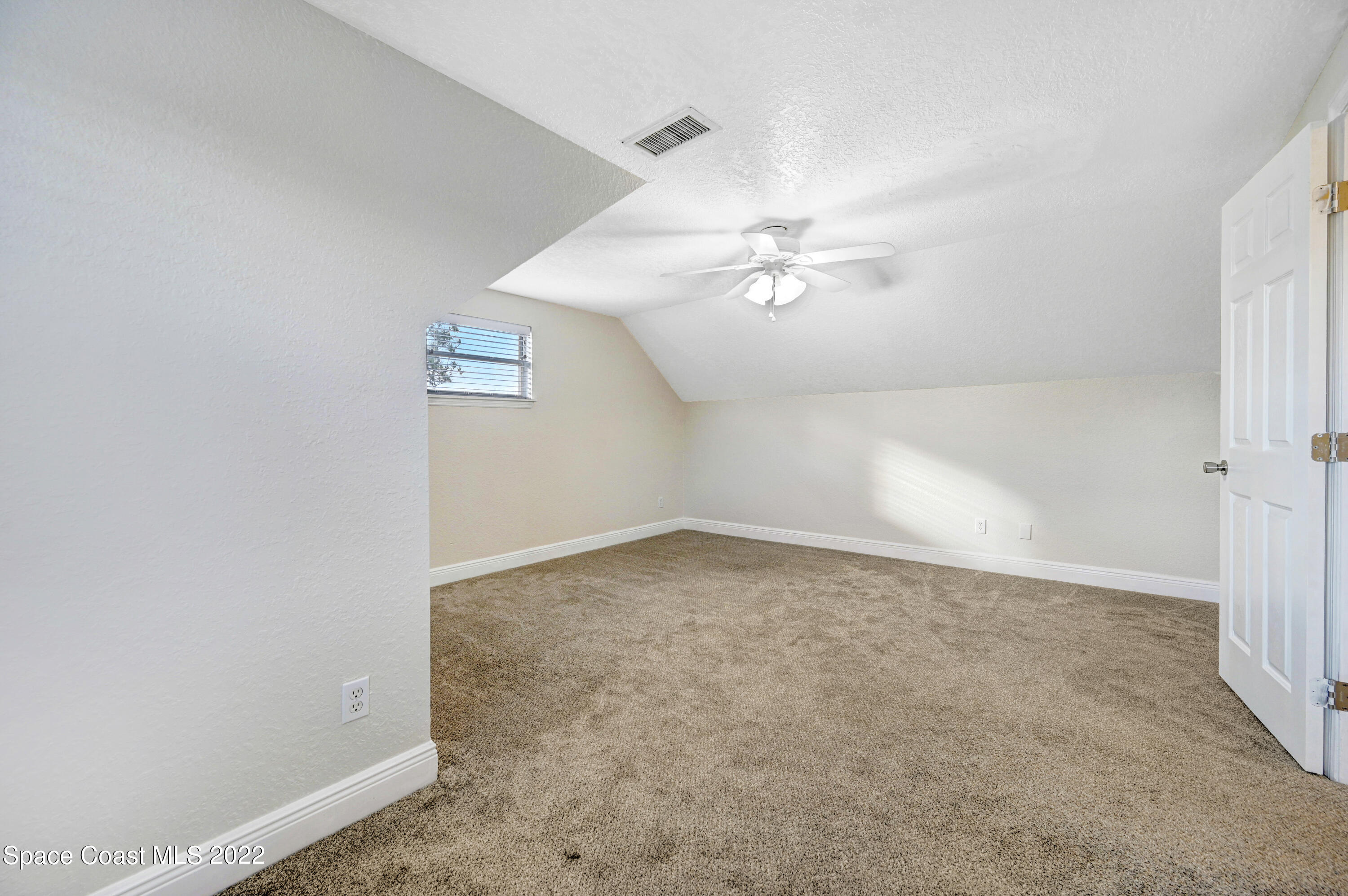 1074 Castile Road Southeast Palm Bay, FL 32909 - Photo 25 of 40 an empty room with a ceiling fan and carpet