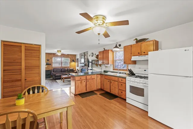 a kitchen with stainless steel appliances a stove a refrigerator a dining table and chairs with wooden floor