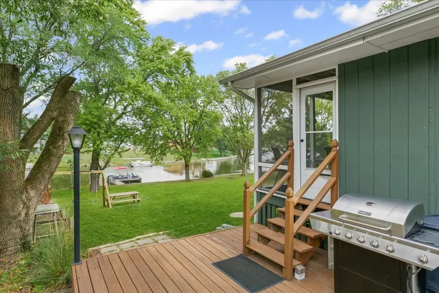 a view of a backyard with table and chairs and a barbeque with potted plants and large trees