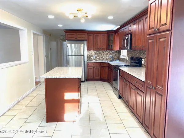a large kitchen with kitchen island granite countertop wooden cabinets a sink and stainless steel appliances