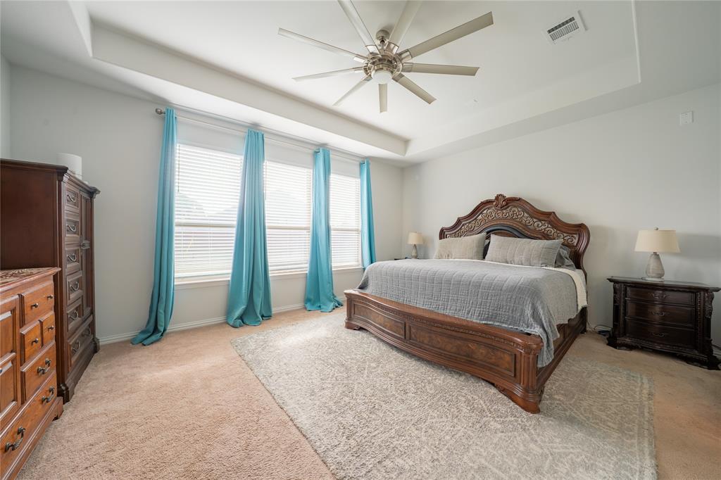 4542 Kipling Avenue Aubrey, TX 76227 - Photo 13 of 34 a bedroom with a large bed and a flat tv screen on dresser