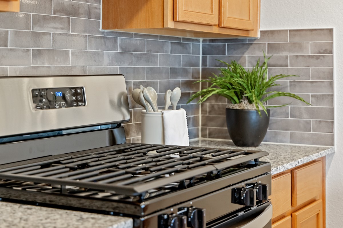 This kitchen has it all—ample storage, generous counter space, and a layout that truly makes it the heart of the home. Pictured here is the stainless steel Whirlpool gas range and closer views of the gorgeous granite countertop and backsplash.