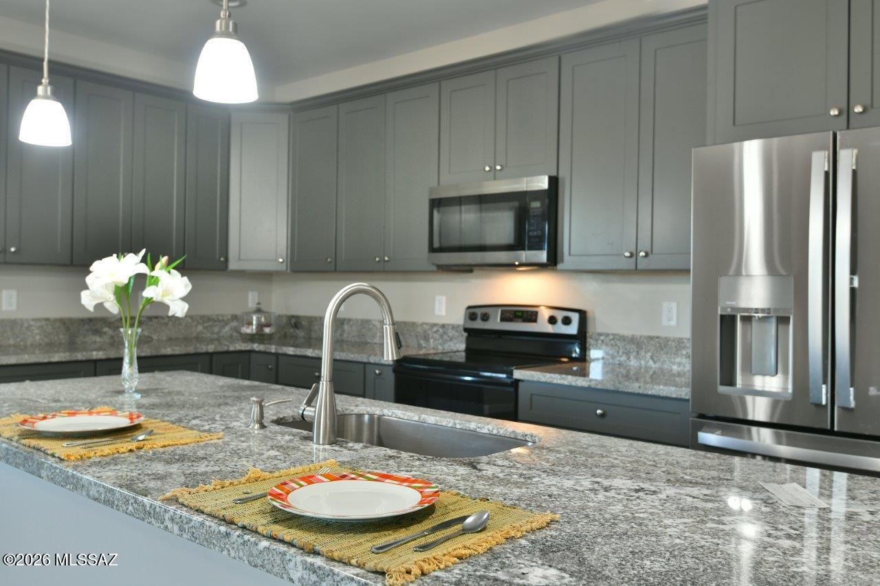 1091 North Vail View Road Vail, AZ 85641 - Photo 13 of 43 a kitchen with kitchen island granite countertop a stove refrigerator and microwave