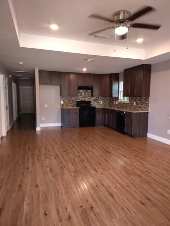 a large kitchen with stainless steel appliances granite countertop a stove and a wooden floors