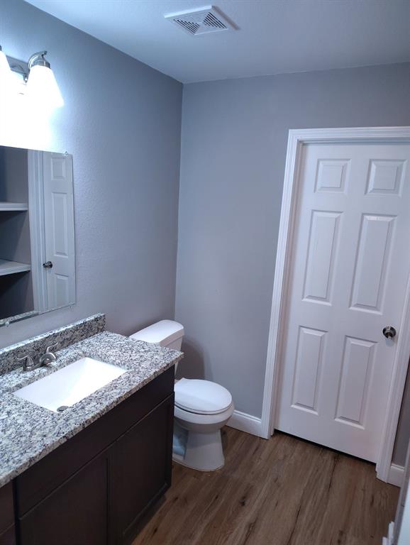 1702 Clark Street Commerce, TX 75428 - Photo 9 of 10 a bathroom with a granite countertop sink toilet and a mirror