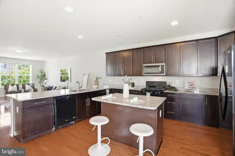 a kitchen with stainless steel appliances granite countertop a sink dishwasher a stove a refrigerator with a dining table and chairs