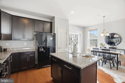 a kitchen with stainless steel appliances granite countertop a refrigerator a stove a sink and a dining table with white cabinets