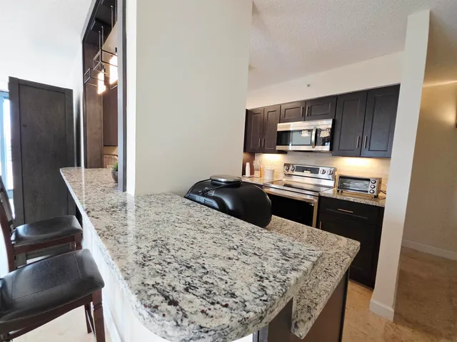 a kitchen with granite countertop wooden cabinets and stainless steel appliances
