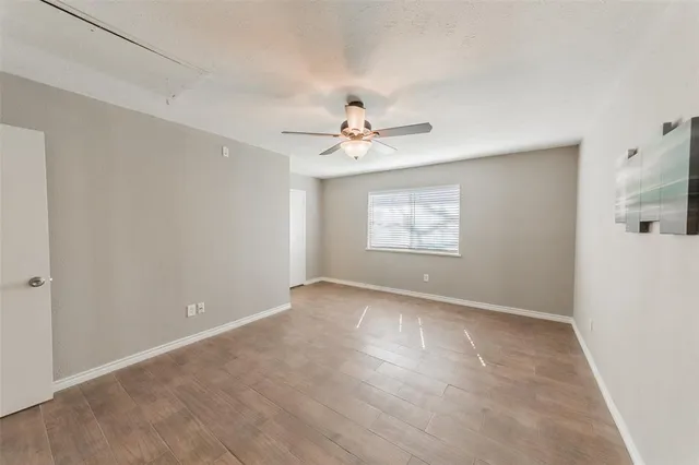 an empty room with windows and fan