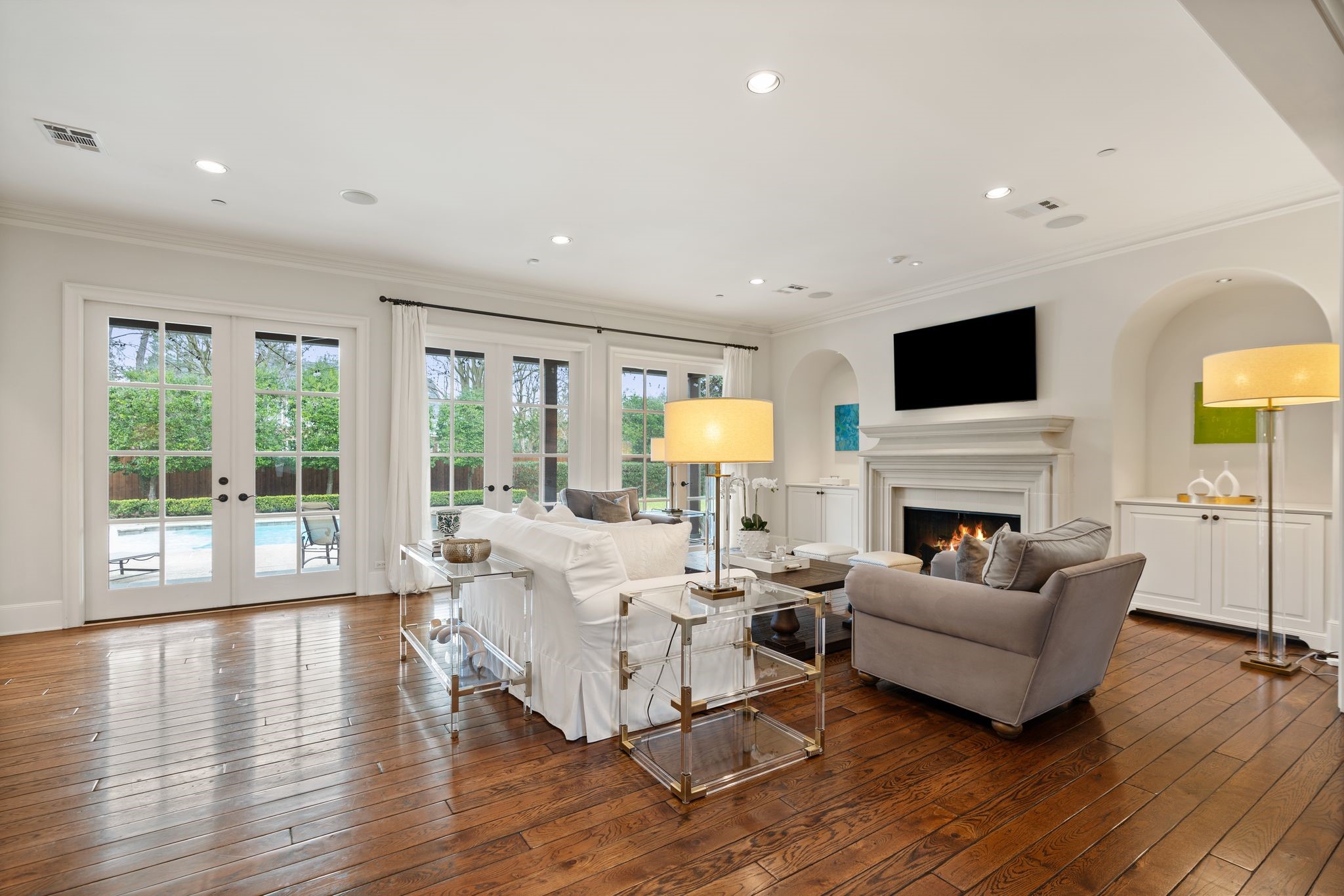 11402 Taylorcrest Road Houston, TX 77024 - Photo 16 of 44 Spacious family room designed for comfortable everyday living & larger gatherings alike. Gas log fireplace w/ cast stone surround & mantel serves as a beautiful focal point, flanked by lit alcoves w/ storage below. Crown molding, recessed lighting, ceiling speakers, drapes & hardwood floors complete the space.