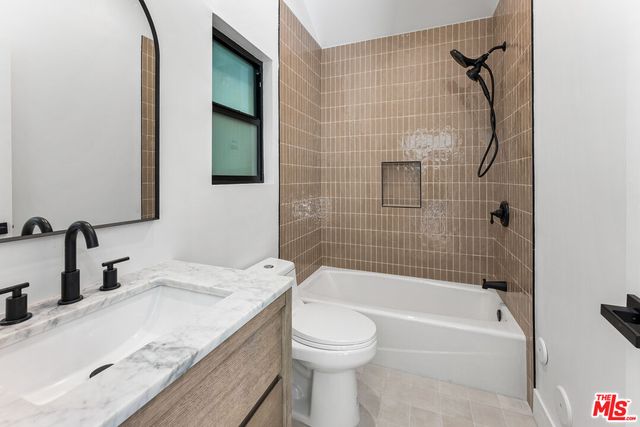 a bathroom with a granite countertop sink a toilet and shower