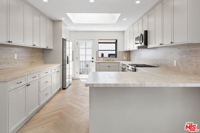 a kitchen with stainless steel appliances granite countertop a sink a stove and white cabinets