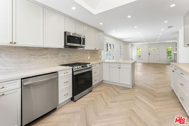 a kitchen with granite countertop white cabinets and stainless steel appliances
