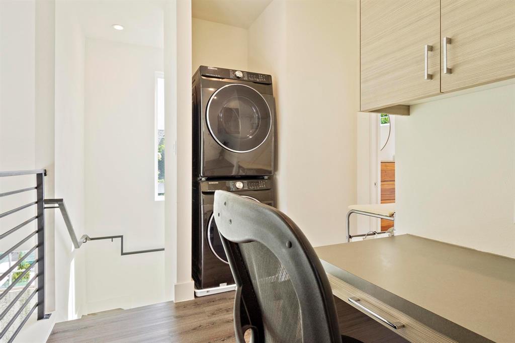 911 Stobaugh Street, Unit 2 Austin, TX 78757 - Photo 21 of 26 Modern laundry area featuring stacked black appliances, wood-finish flooring, and light-toned cabinetry with brushed nickel hardware