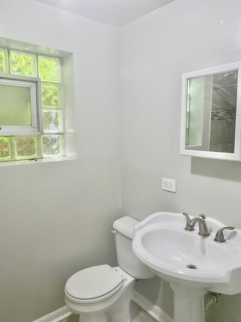 10924 South Indiana Avenue, Unit G Chicago, IL 60628 - Photo 6 of 9 a white toilet sitting next to a bathroom sink