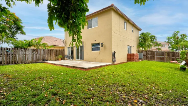a view of a house with backyard and a tree