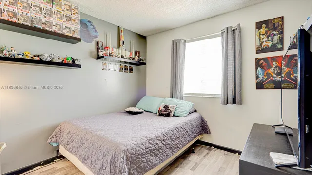 a bedroom with a bed and dresser with wooden floor