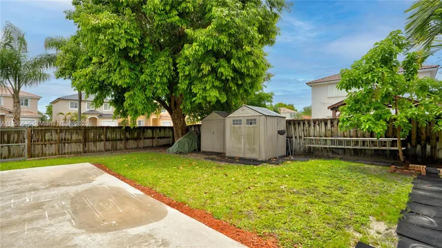 a view of a backyard with large trees and wooden fence