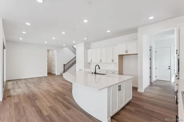 a kitchen with a sink stainless steel appliances and wooden floor