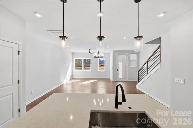 a kitchen with stainless steel appliances granite countertop a sink a window and a wooden floor