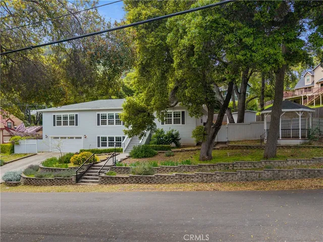 a front view of a house with trees and plants