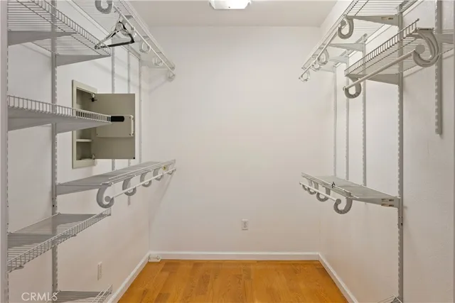 a view of an empty room with wooden floor and a ceiling fan