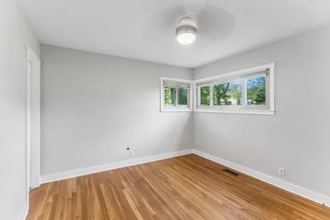 a view of empty room with wooden floor and fan