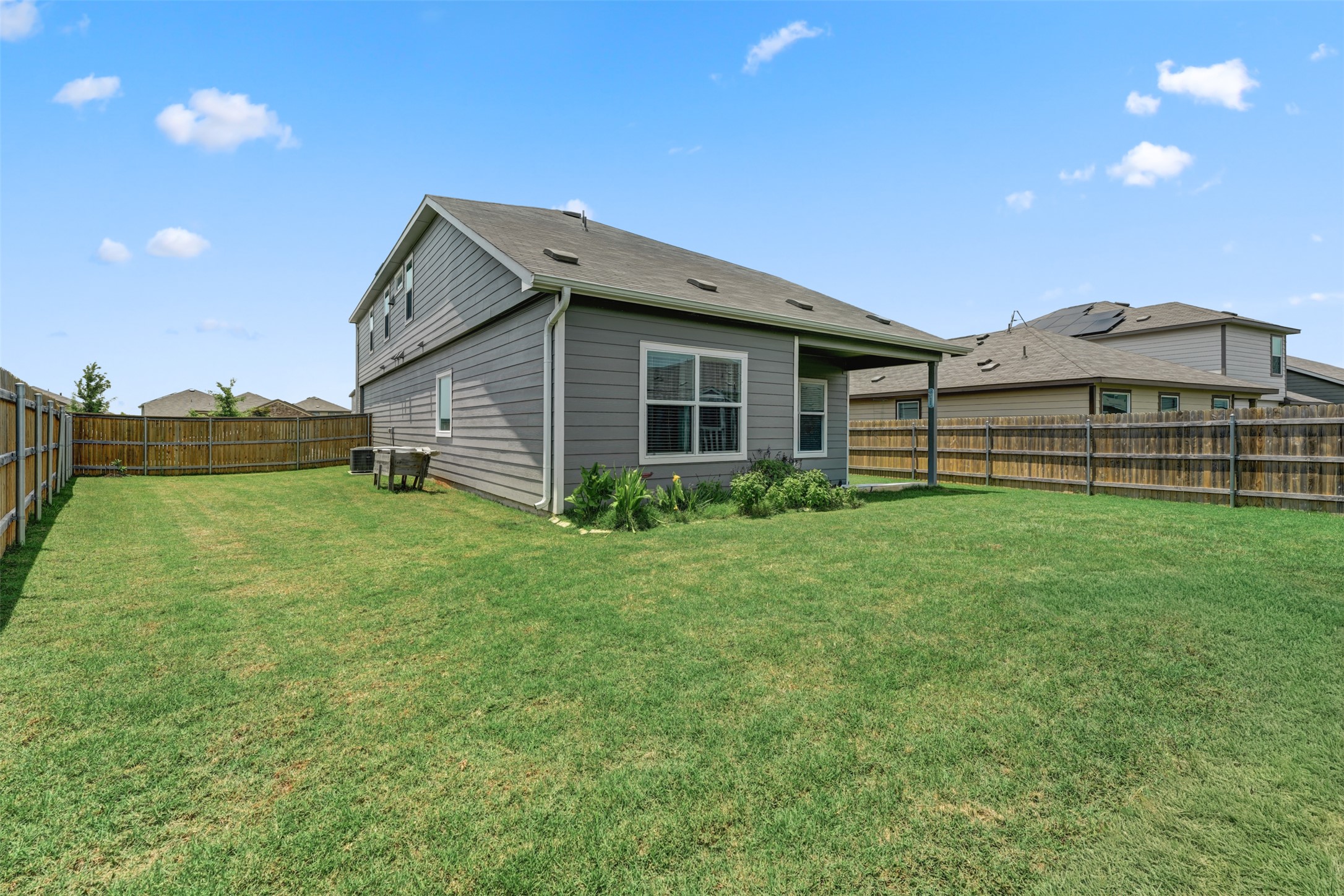 413 Perfect World Loop Jarrell, TX 76537 - Photo 36 of 39 A spacious backyard with vibrant green grass, fully fenced for privacy and outdoor enjoyment.