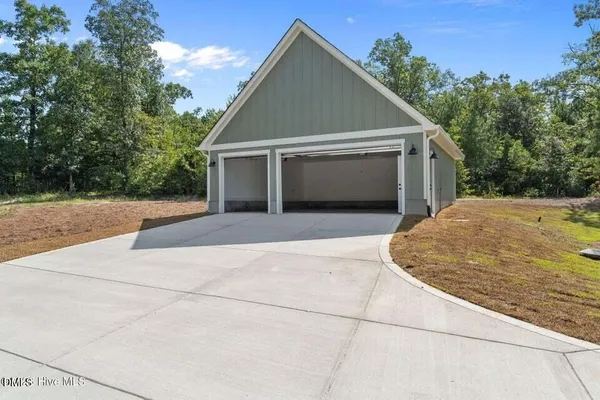 a view of house with garage and trees in the background