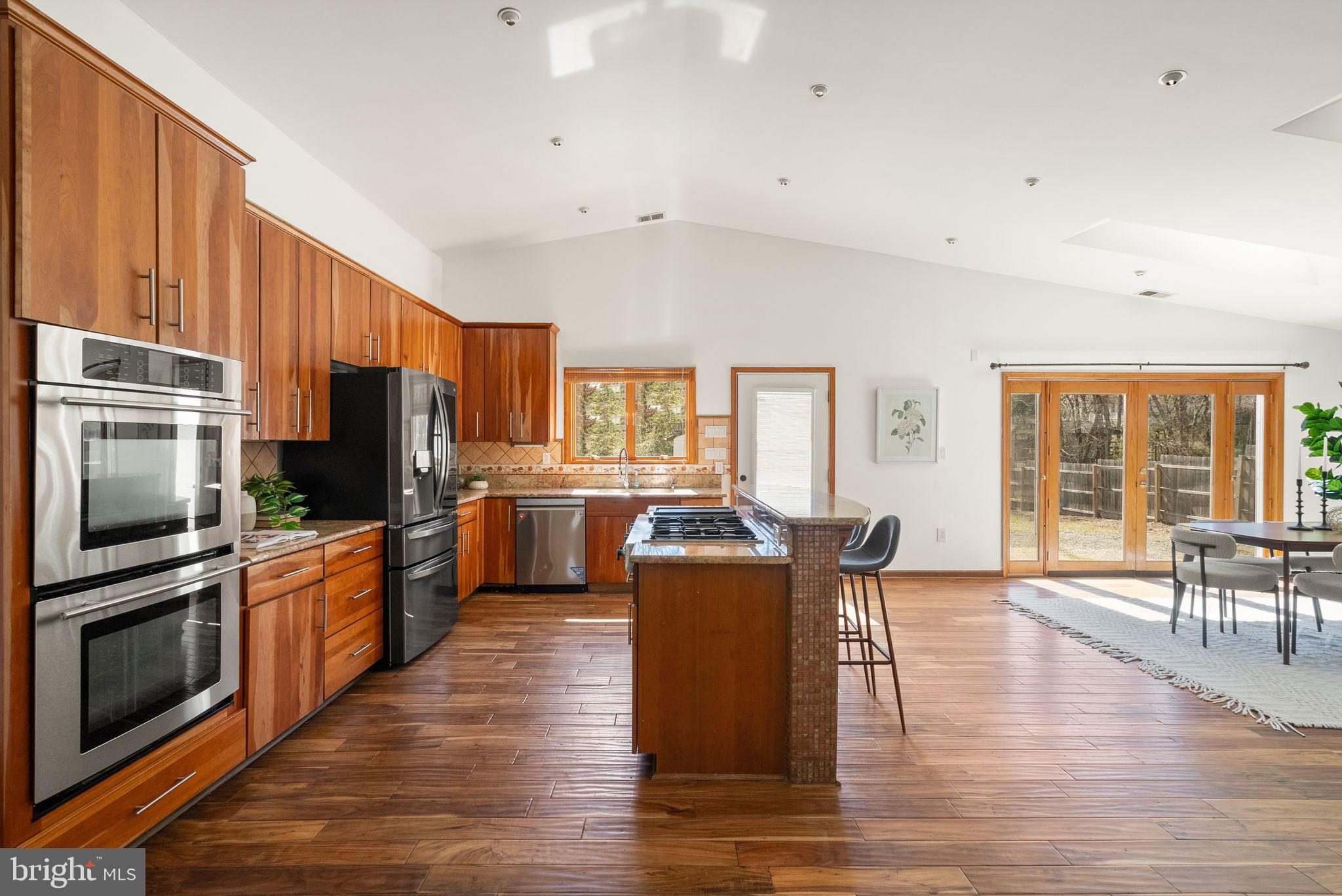 8737 Redman Street Springfield, VA 22153 - Photo 12 of 62 a large kitchen with stainless steel appliances granite countertop a stove top oven a sink dishwasher a dining table and chairs with wooden floor