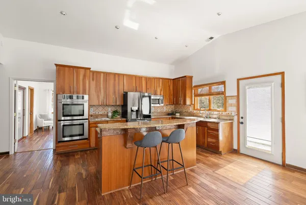 a kitchen with stainless steel appliances granite countertop a stove top oven a sink dishwasher and wooden cabinets with wooden floor