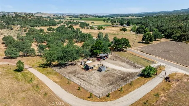 an aerial view of a house with large trees and outdoor seating