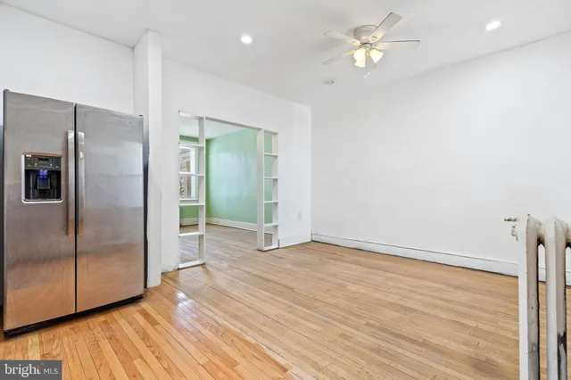 a view of a kitchen with wooden floor a ceiling fan and refrigerator in a kitchen