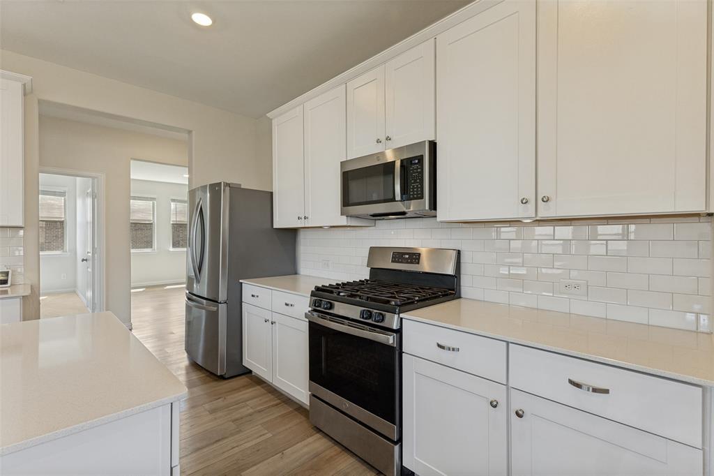 1237 Almond Road Azle, TX 76020 - Photo 7 of 24 a kitchen with stainless steel appliances white cabinets and a stove top oven
