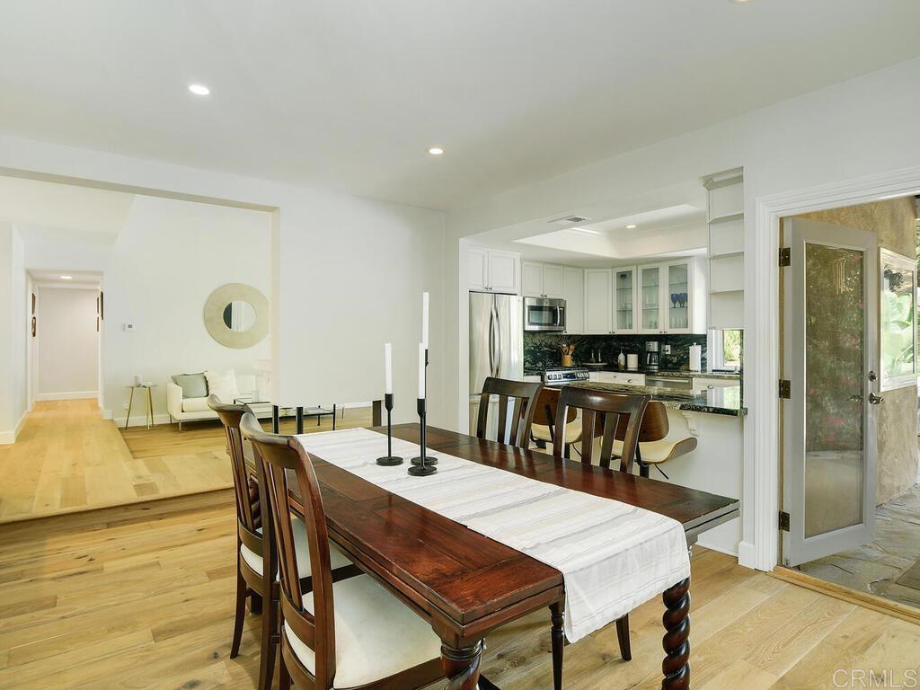 14146 Mango Drive Del Mar, CA 92014 - Photo 11 of 33 a view of a dining room and livingroom with furniture wooden floor a rug a painting and a chandelier