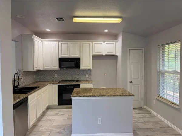 a kitchen with kitchen island granite countertop a sink a counter top space and cabinets
