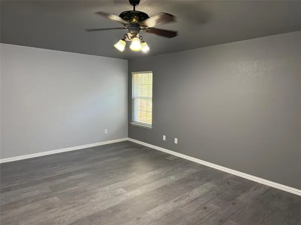 an empty room with a window and a chandelier fan