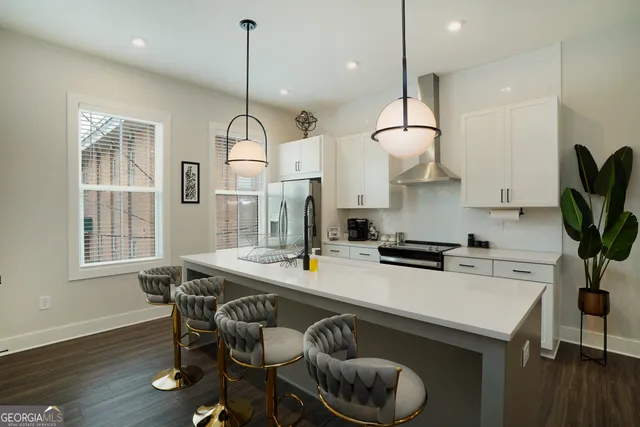 a kitchen with stainless steel appliances granite countertop a stove a sink dishwasher a dining table and chairs with wooden floor