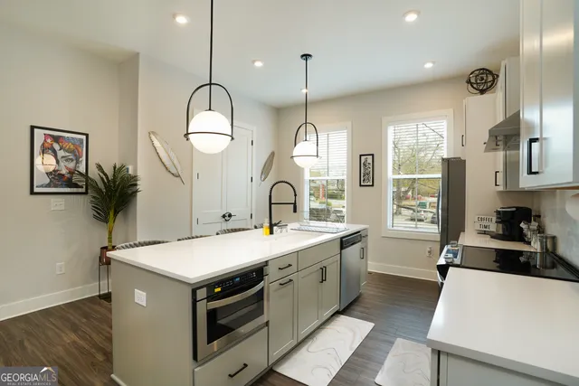 a large kitchen with kitchen island a large counter space a sink stainless steel appliances and cabinets