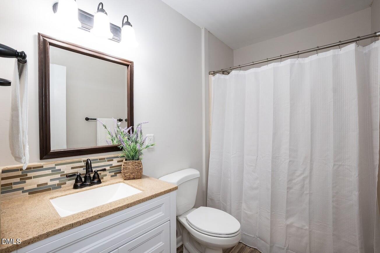 4000 Donna Road Raleigh, NC 27604 - Photo 33 of 58 a bathroom with a sink a toilet a mirror and shower curtain