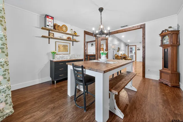 a dining room with wooden floor a chandelier a wooden table and chairs