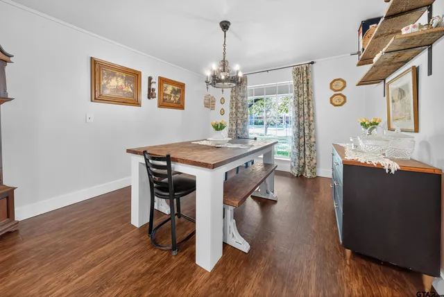 a dining room with wooden floor a chandelier a wooden table and chairs