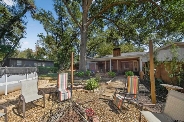 a view of a patio with table and chairs potted plants and large tree