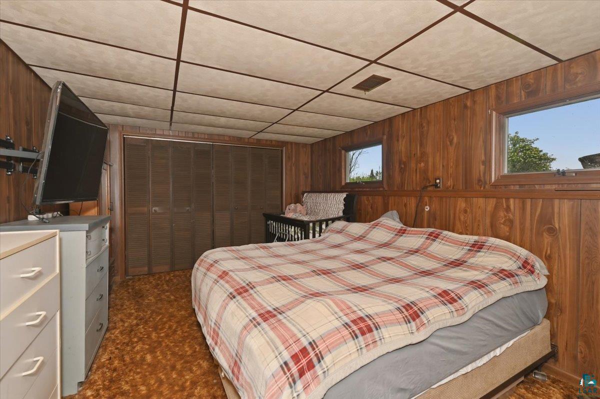 5190 County Road M Gordon, WI 54838 - Photo 18 of 31 Room featuring wood paneling, multiple windows, a drop ceiling, and wall-to-wall carpeting